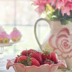 Bowl full of strawberries in a pink kitchen table setting