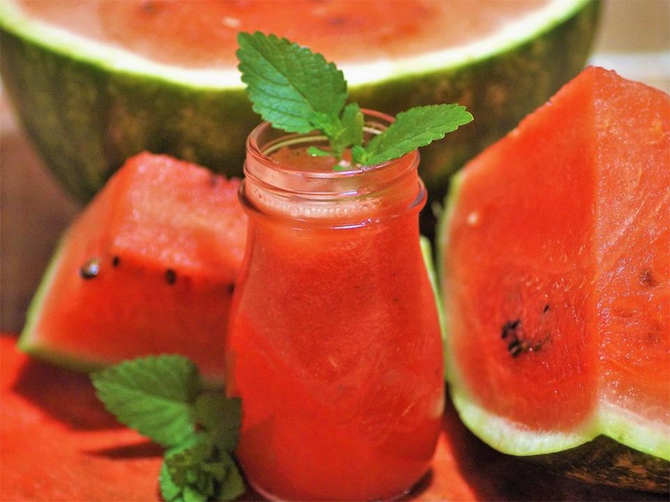 A few slices of watermelon and a watermelon smoothie with mint leaves as garnish