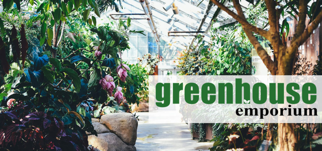 Interior of a huge greenhouse with lots of plants and the Greenhouse Emporium Logo