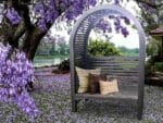 The Adelaide Dove Gray Arbor With Bench and Pillows in a garden