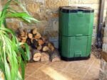 Aerobin 400 Insulated Composter - by the wall with a pile of woods on its side
