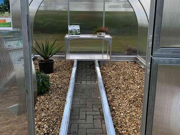Open door front view of Arcus Greenhouse with plants and a shelf inside