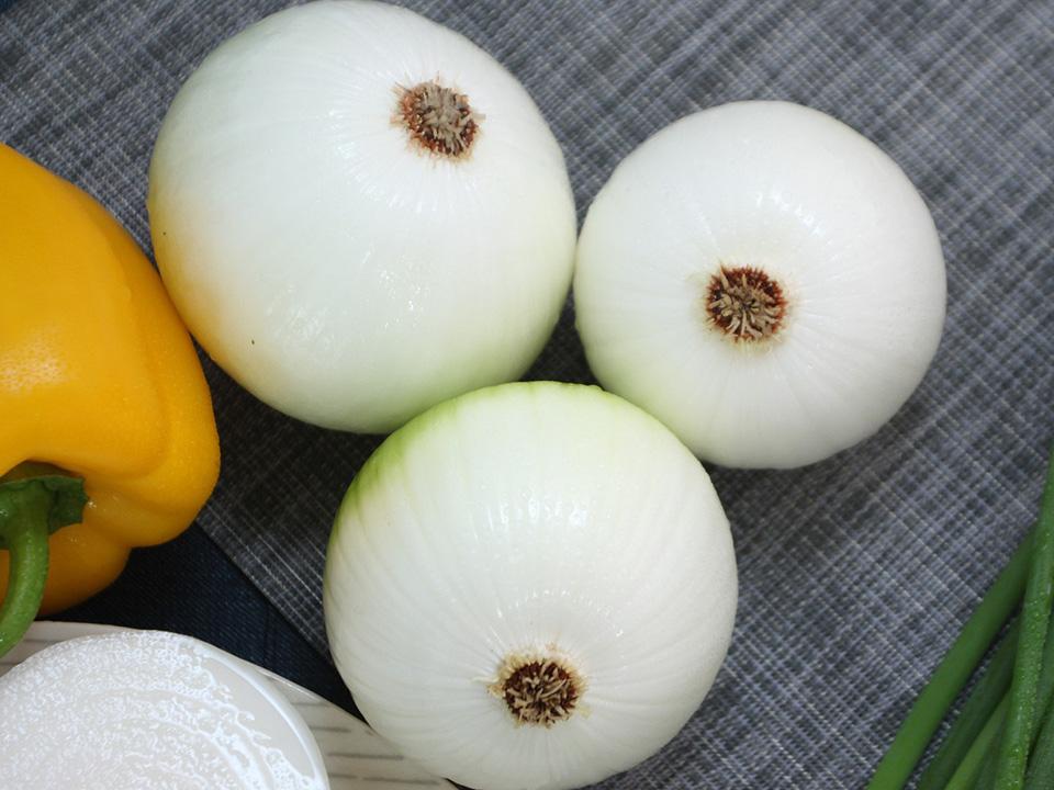 Three green onions with a yellow pepper on the left side