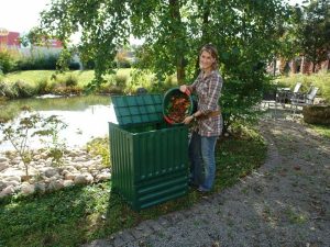 A woman on the right side pouring leaves into Eco King 400 Compost Bin