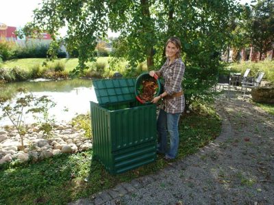 A woman on the right side pouring leaves into Eco King 400 Compost Bin