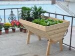 Eden V-Shaped Solid Wood Garden Table with plants on a patio