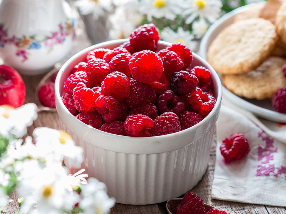 Raspberries in a white bowl on a table