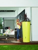 Lemon Yellow High Gloss Rain Barrel & Planter. A woman on the left side watering the plants on top of the barrel.