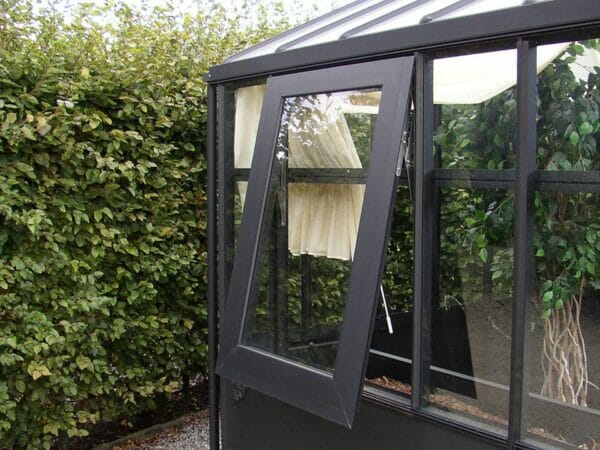 Black glass greenhouse featuring a side window that is hinged at the top