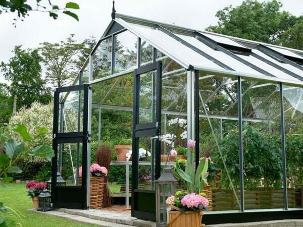 Juliana Gardener Greenhouse 12ft x 19ft - 3mm toughened glass - front and side view - in a garden