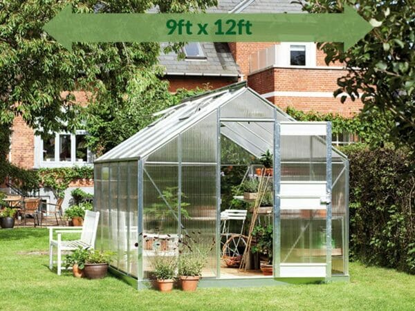 Juliana Junior Greenhouse 9ft x 12ft - 6 mm Polycarbonate - in a garden - green arrow with dimension on top