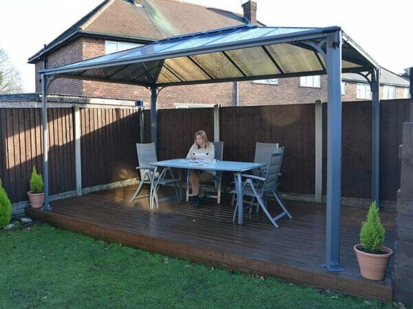 Martinique Hard Top Gazebo with a dining set up in a garden