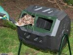 Dropping organic waste into the Mr. Spin Dual Compartment Compost Tumbler with a shovel