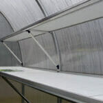 White and silver aluminum shelves with supports at the bottom in a Riga Greenhouse