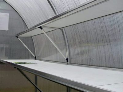 White and silver aluminum shelves with supports at the bottom in a Riga Greenhouse
