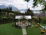 Janssens T-Shaped Royal Victorian Orangerie 10ft x 16ft in a garden with great view of mountains and a lake