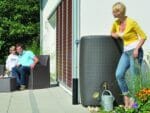 Dark brown Sunda Wicker Look Rain Barrel outdoor with a woman on the right side leaning toward it