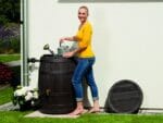 A woman on the left side of VINO Rain Barrel holding a sprinkler