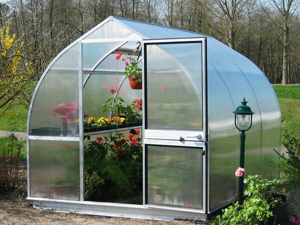 One of the Riga S Greenhouse line in a garden - gothic-arch shape with a barn-style door