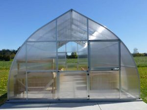 One of the Riga XL Greenhouse line in a garden - gothic-arch shape with two barn-style doors
