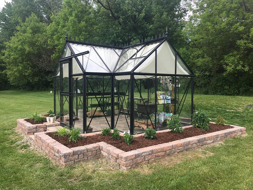 a metal framed greenhouse on a cement foundation