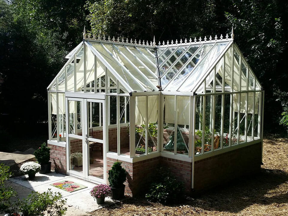 White orangerie greenhouse on a stem wall built with bricks