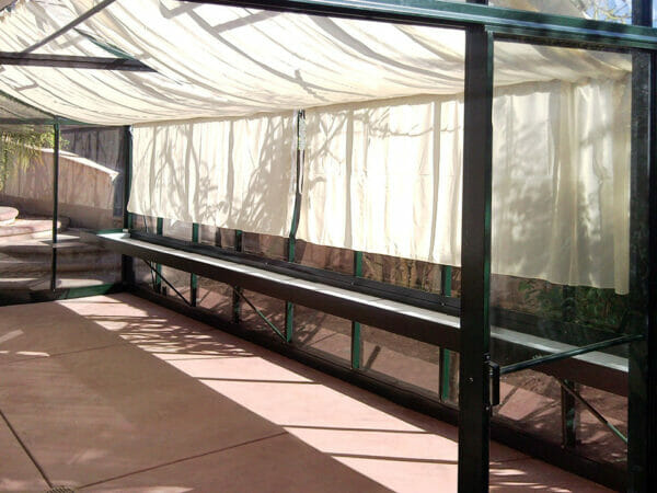 View inside an empty Royal Victorian Greenhouse with shade curtains and a shelf