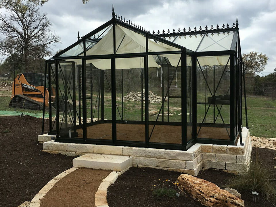 Glass greenhouse on a foundation made of bricks and soil flooring