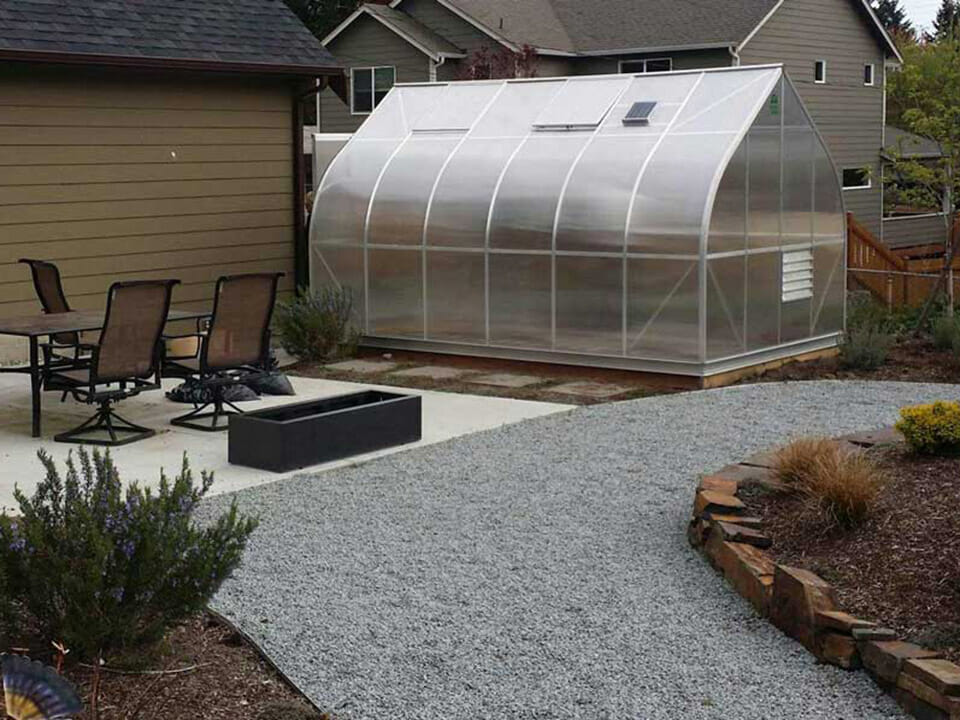 Climapod greenhouse in the backyard next to a patio