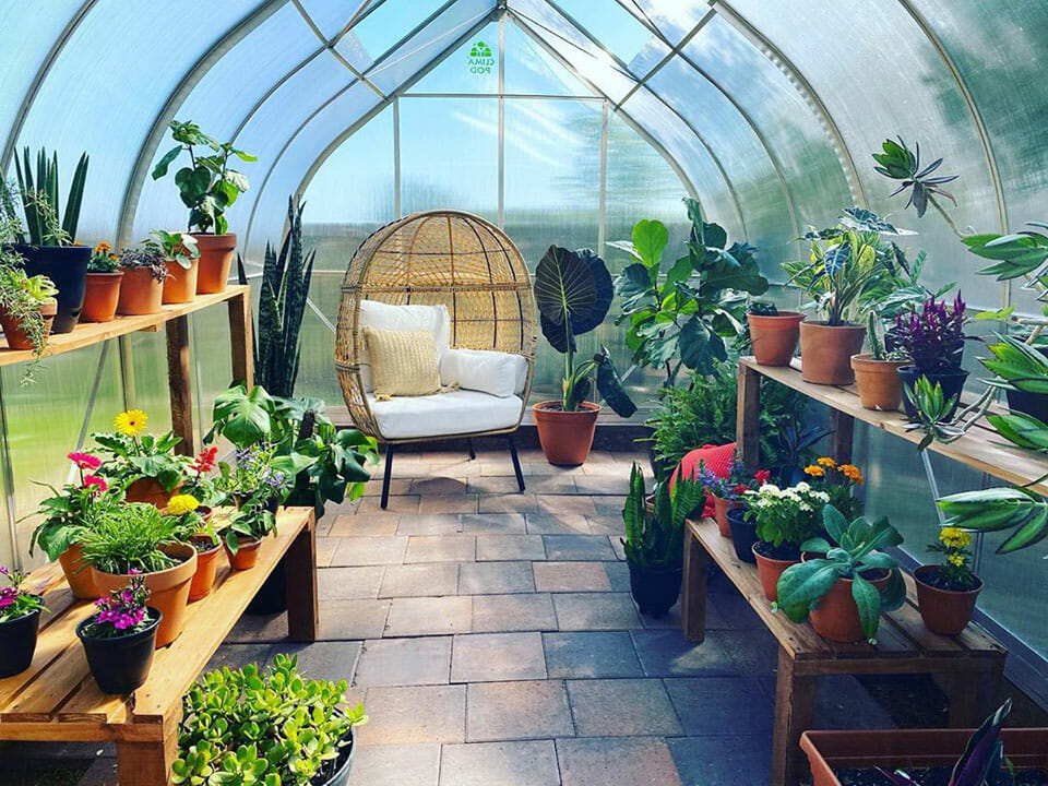 Interior of a Climapod greenhouse with shelves, plants, and a chair