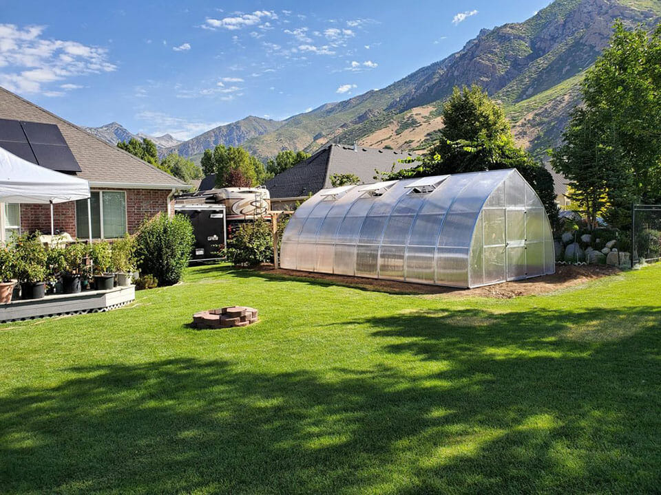 Riga greenhouse in a garden behind a house with mountains in the background