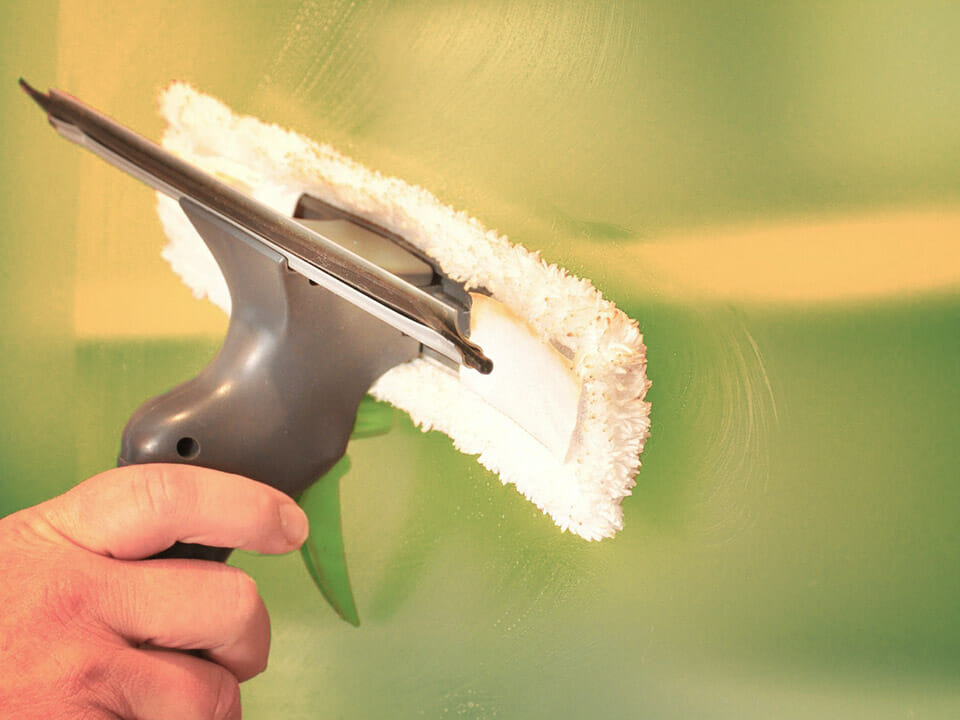 Person (hand is visible) cleaning glass with a squeegee tool