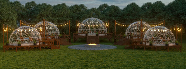 Group of five geodesic domes on decking with lighting on interior and fire pit in center of grouping, domes with clear vinyl cover and powder coated steel frames