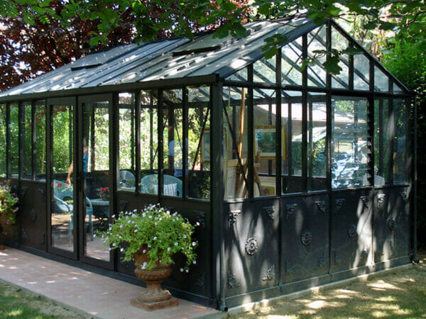Retro Royal VI36 4mm glass greenhouse with black frame, decorative panels, interior filled with patio furniture and artwork