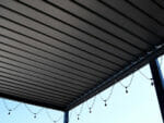 View of Selt System Sunbreaker 400 Pergola roof from underneath structure, black, slats closed, shown with string lights