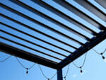 View of Selt System Sunbreaker 400 Pergola roof from underneath structure, black, slats open, shown with string lighting installed