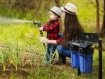 GrowMax Super Grow 800 installed in garden where a mother with her child are watering directly from the unit