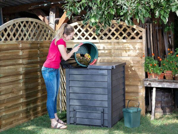Woman emptying bucket of organic materials into gray Thermo Wood Composter
