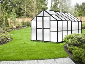 Exterior front and side view of MONT Growers 8x12 greenhouse with black frame and polycarbonate panels, outside on lawn, doors closed