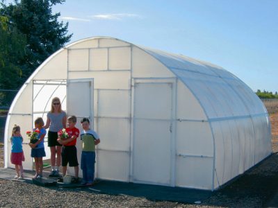Woman and children standing at doorway of Conservatory greenhouse, located on gravel