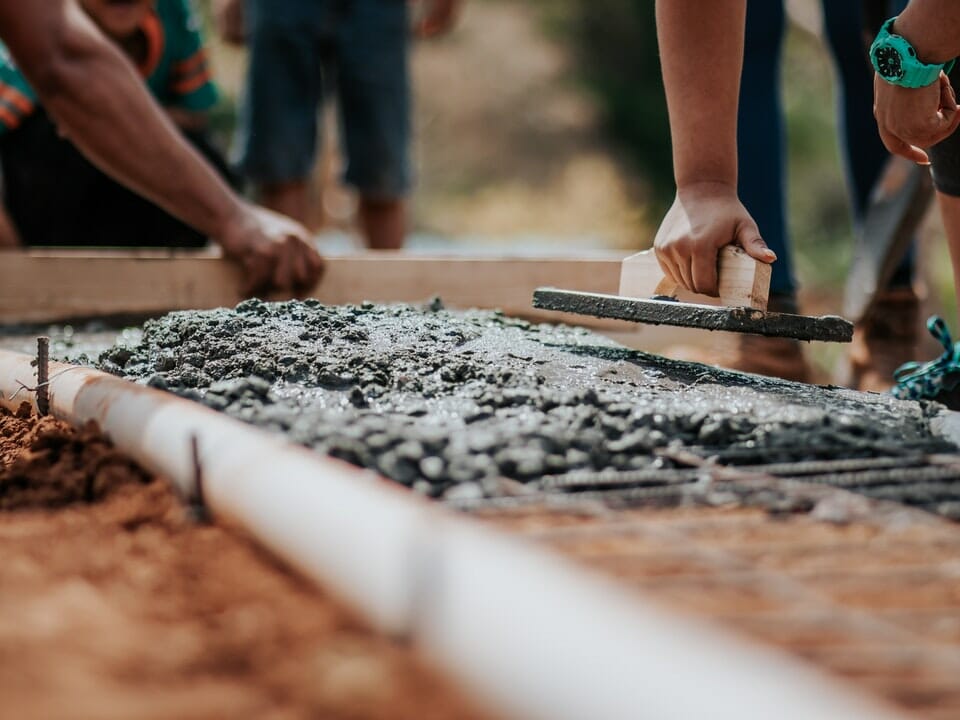 View of workers' hands leveling concrete for a foundation