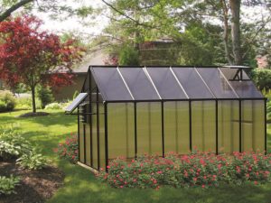 MONT 8x12 Greenhouse - Moheat Edition with a solar fan and tinted roof panels in a garden setting