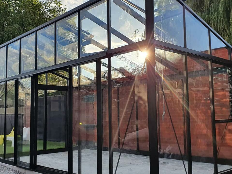 Empty Janssens Modern Glass Greenhouse in a backyard