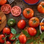 Variety of tomatoes in a table with the text: How To Grow Tomatoes in a Greenhouse