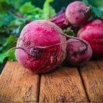 Beet roots with leaves attached with text: How to Grow Beets in your greenhouse?