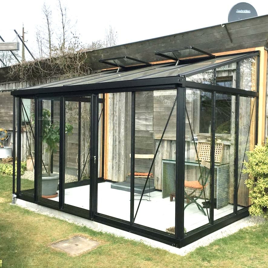 Small lean-to greenhouse on house wall, black frame, glass greenhouse