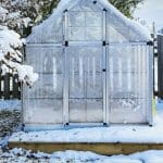 Snow covered greenhouse with text: Heating and Insulating Your Greenhouse in Winter
