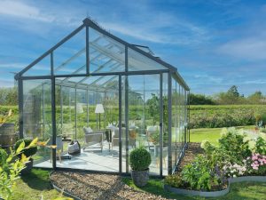 Exterior view of Livingten Insulated Glass Greenhouse in backyard settings with field behind it
