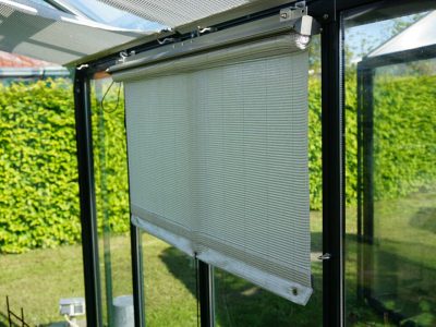 Side-mounted Retractable Roll-up Shade Curtains installed on the side wall of a greenhouse and partially unrolled