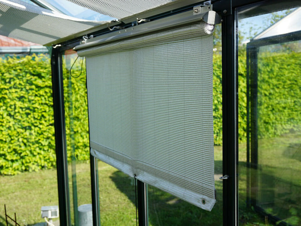 Side-mounted Retractable Roll-up Shade Curtains installed on the side wall of a greenhouse and partially unrolled
